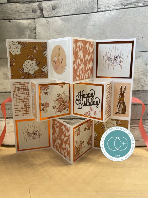 Foldable card with various designs on a wooden surface, featuring a 'Happy Birthday' message.