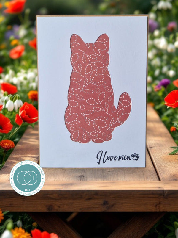 Card with a cat silhouette and 'I love you' text on a wooden surface with flowers in the background
