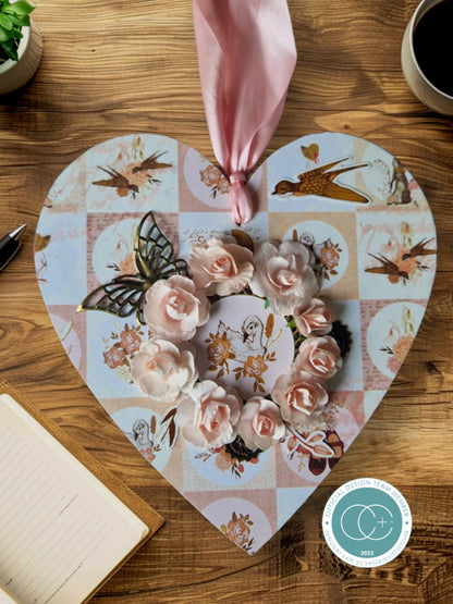 Heart-shaped decorative mat with floral and bird design on a wooden surface