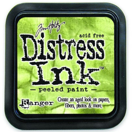 A round container of Tim Holtz Distress Ink in Peeled Paint color, with label and branding visible.