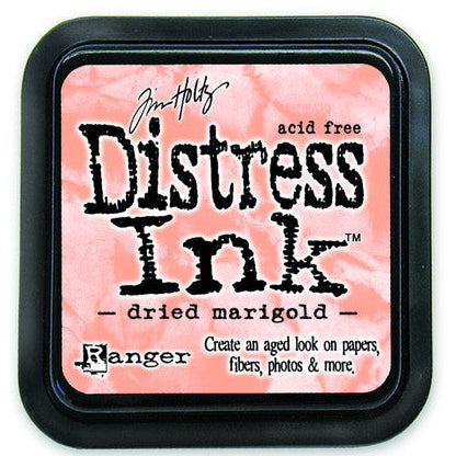 A Distress Ink Pad by Ranger in a Dried Marigold color, housed in a black plastic container with a pink-colored lid.